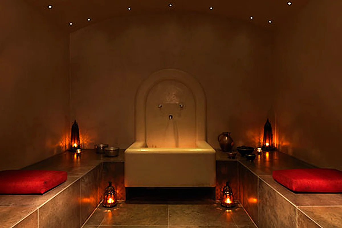 Candlelit Dolphin Square Spa hammam with tiled benches and red cushions