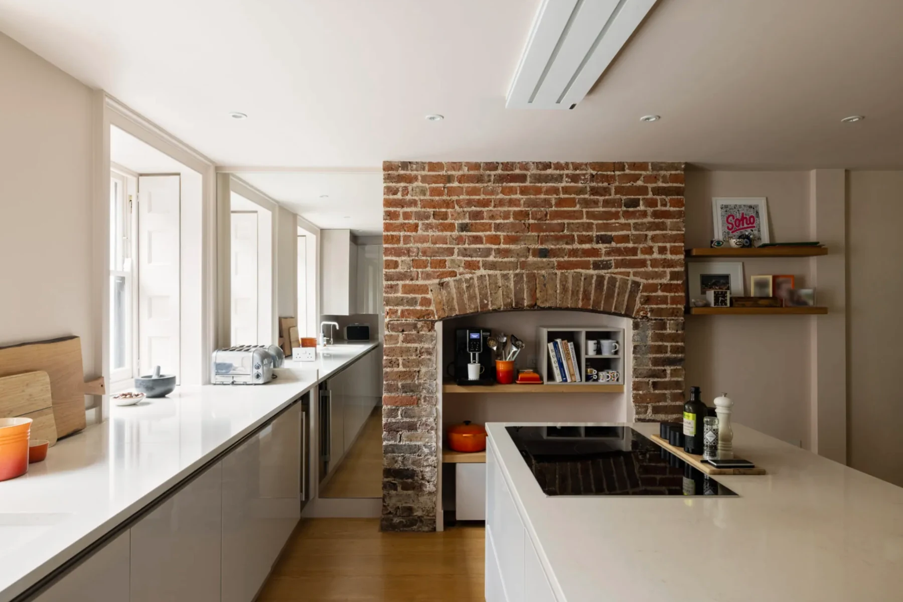 Contemporary kitchen arranged around an original exposed brick fireplace