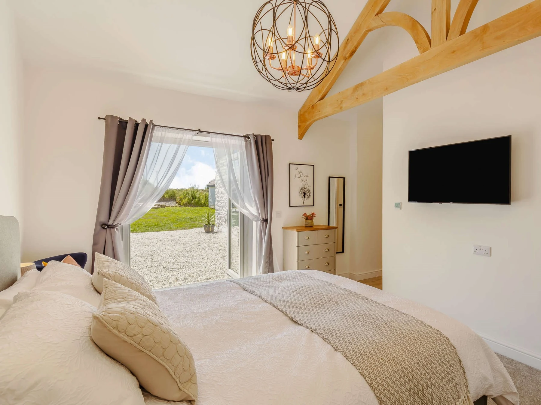 Prime residential bedroom with exposed timber roof structure and garden access