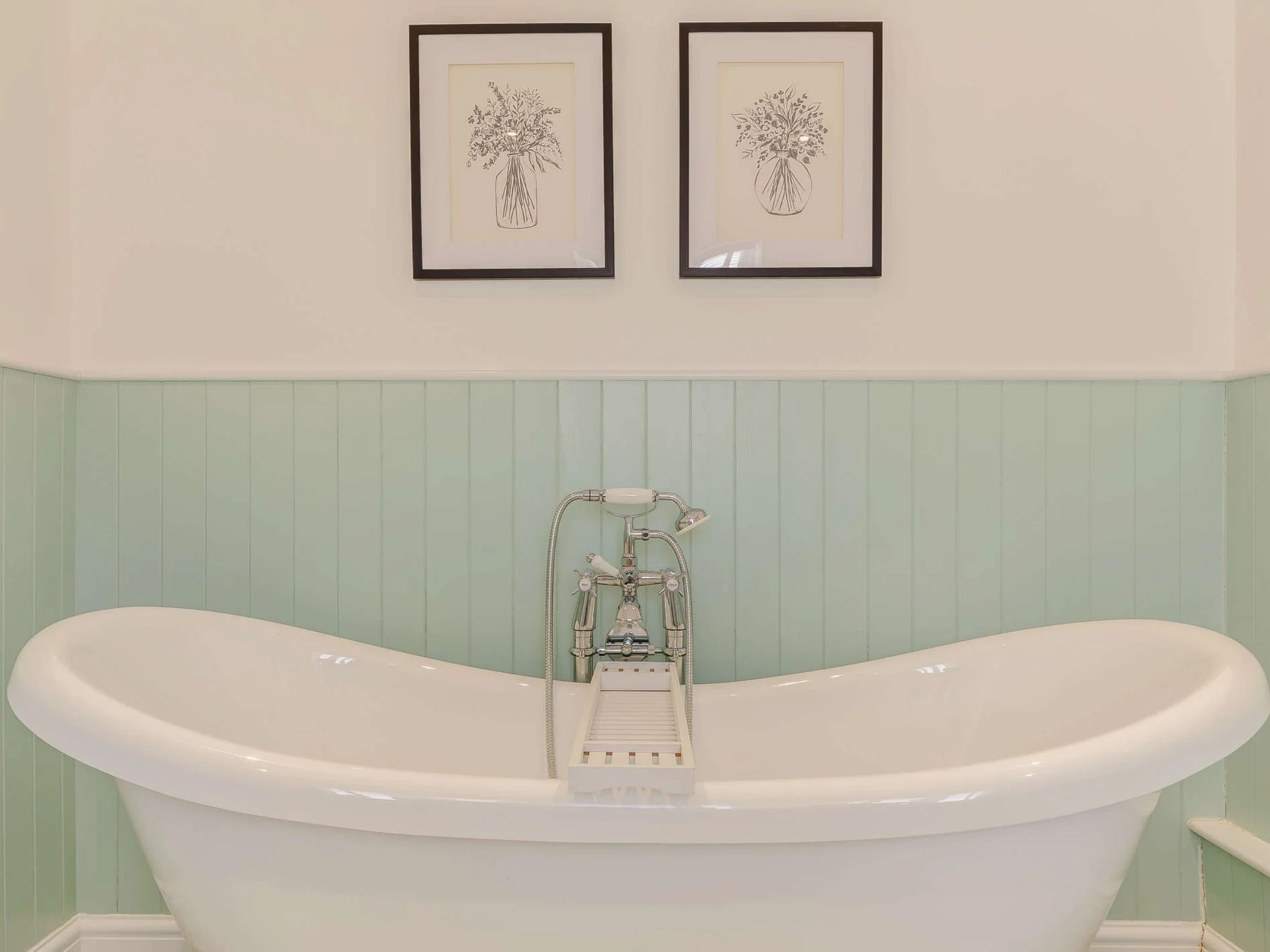 Freestanding bath with pale green timber wall panelling