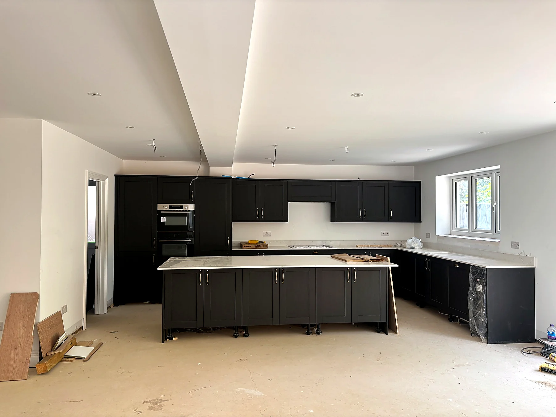 Completed residential kitchen with dark cabinetry, stone worktops and central island